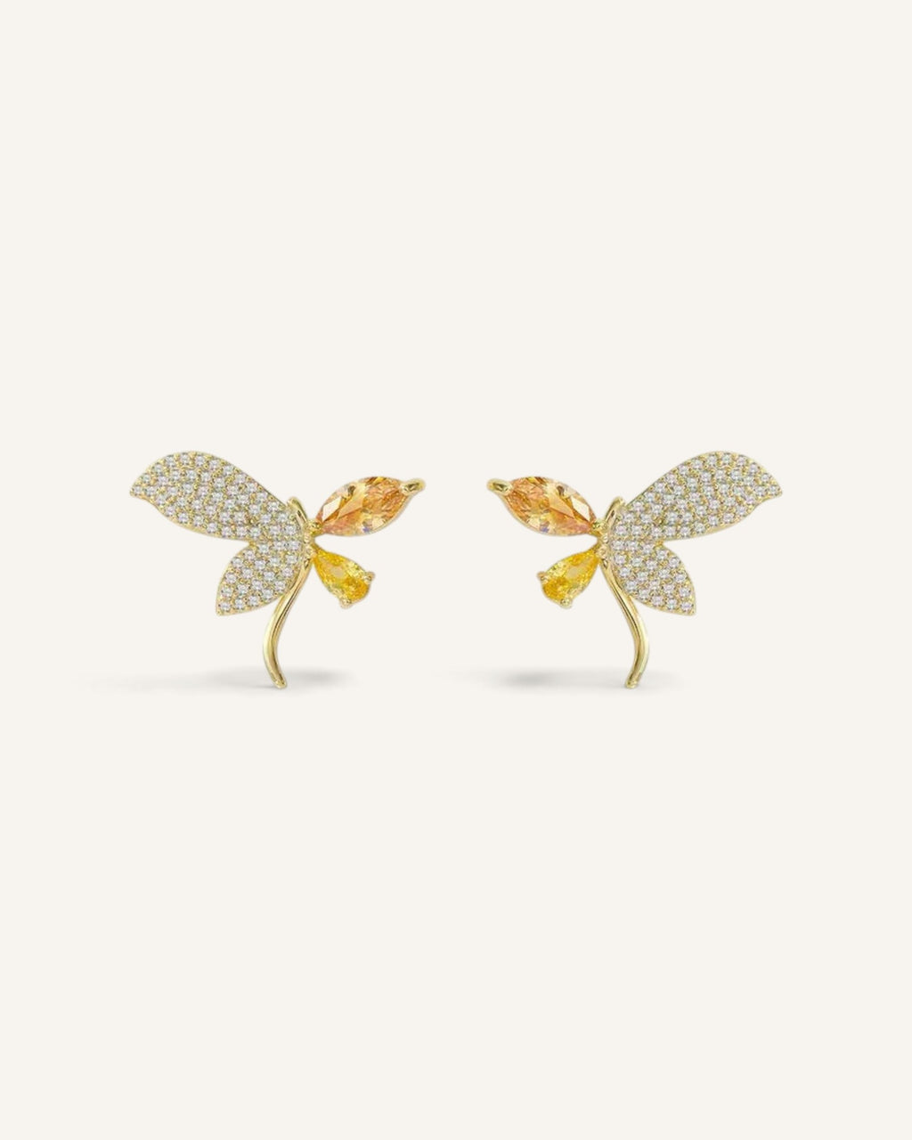 Lunéra de Paris asymmetric butterfly stud earrings in gold-tone alloy with amber crystals and micro-pavé detailing.