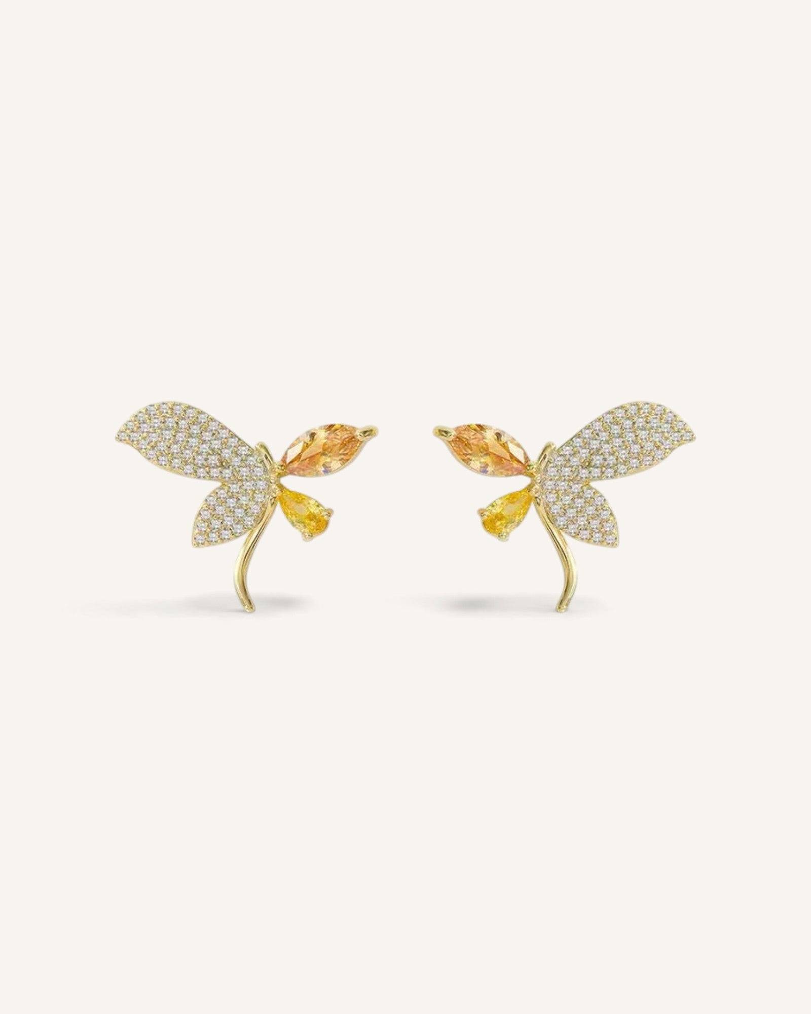 Lunéra de Paris asymmetric butterfly stud earrings in gold-tone alloy with amber crystals and micro-pavé detailing.