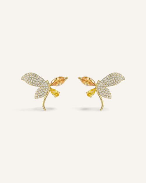 Lunéra de Paris asymmetric butterfly stud earrings in gold-tone alloy with amber crystals and micro-pavé detailing.