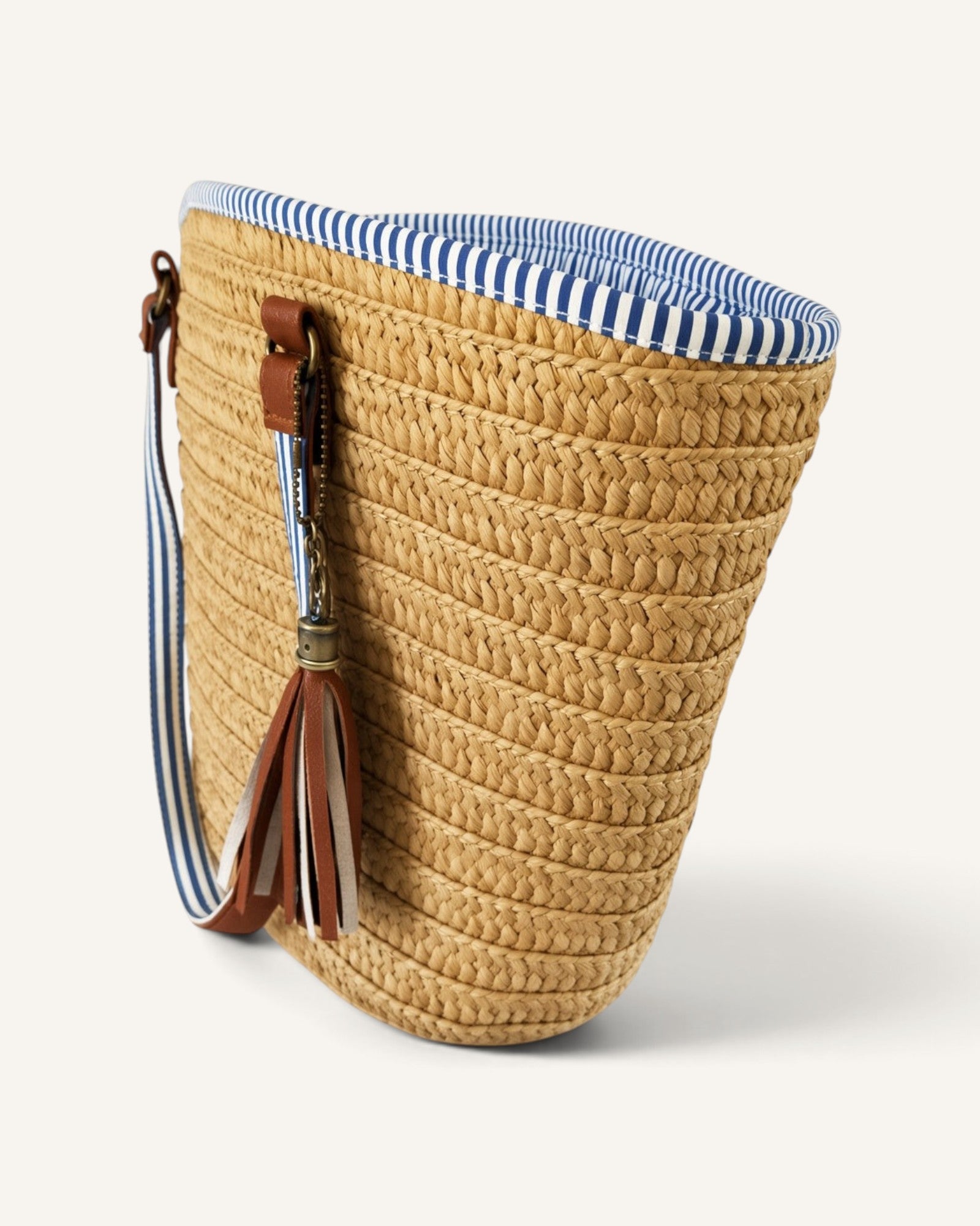 Lunéra de Paris beige woven tote bag with blue and white striped interior, shoulder straps, and a hanging tassel.