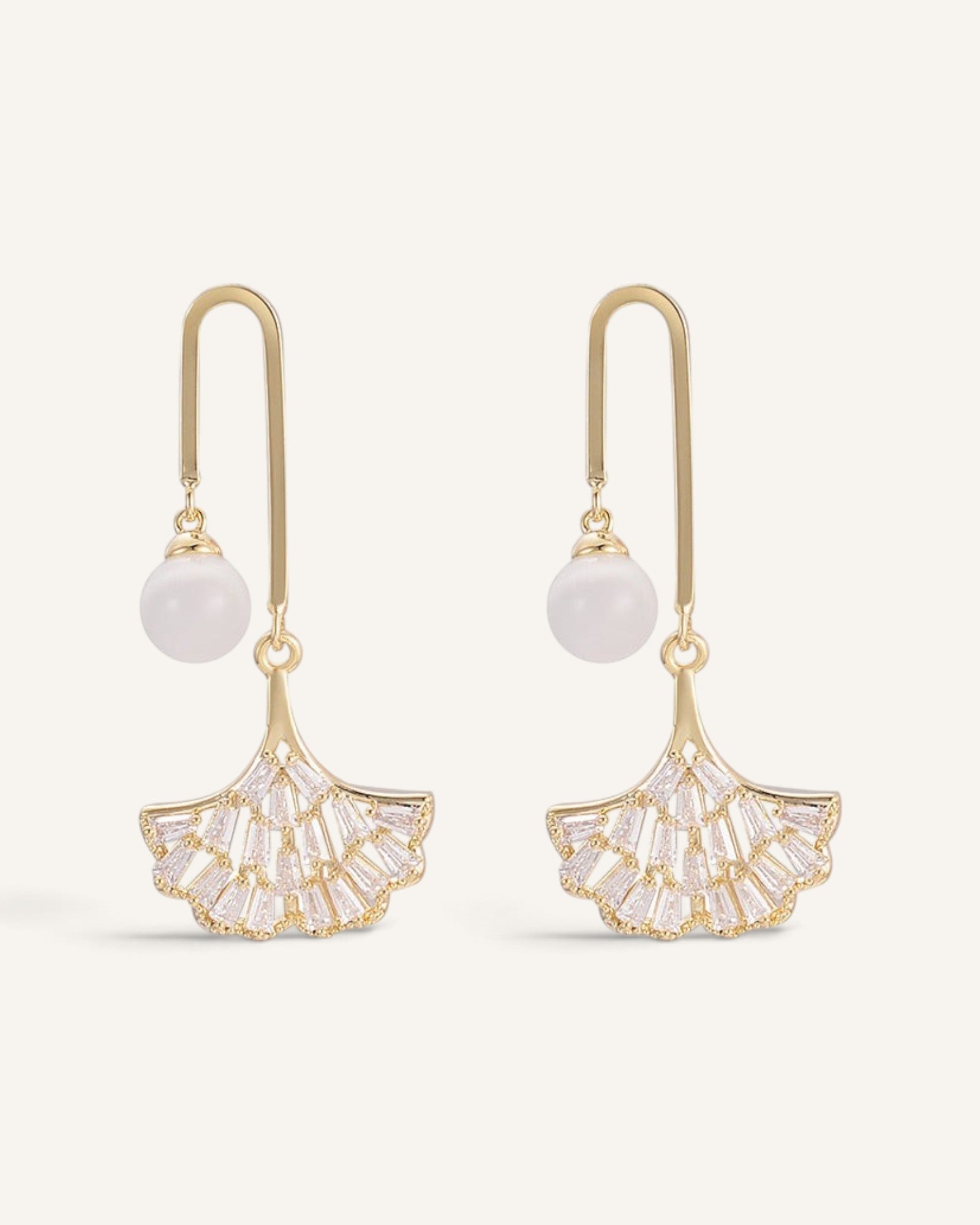 Lunéra de Paris gold ginkgo drop earrings with baguette crystals and a white bead on a u-bar hook design.