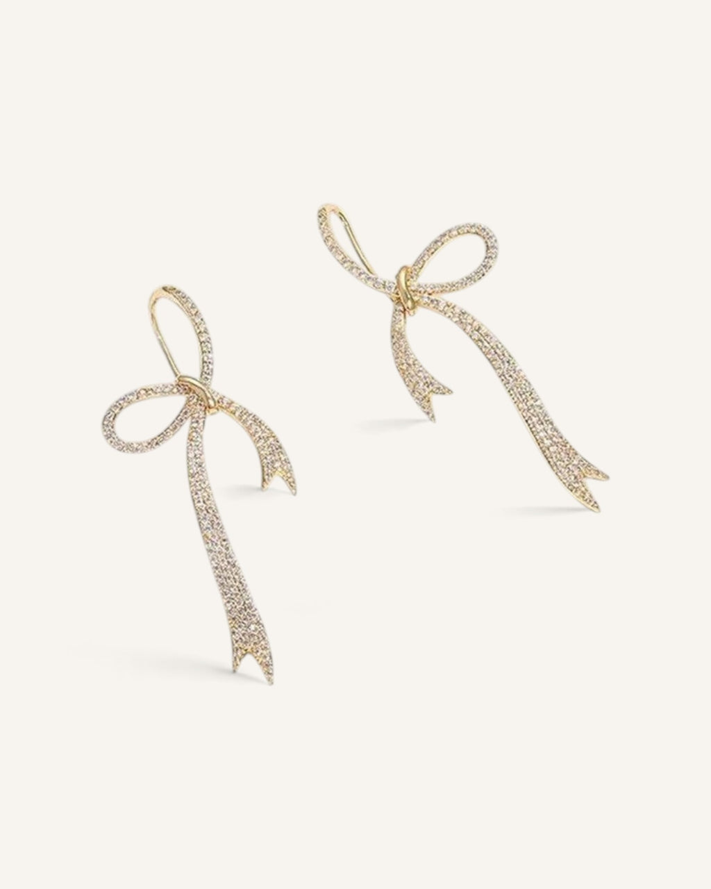 Lunéra de Paris gold-tone bow dangle earrings featuring delicate sparkling crystal accents on a light background.