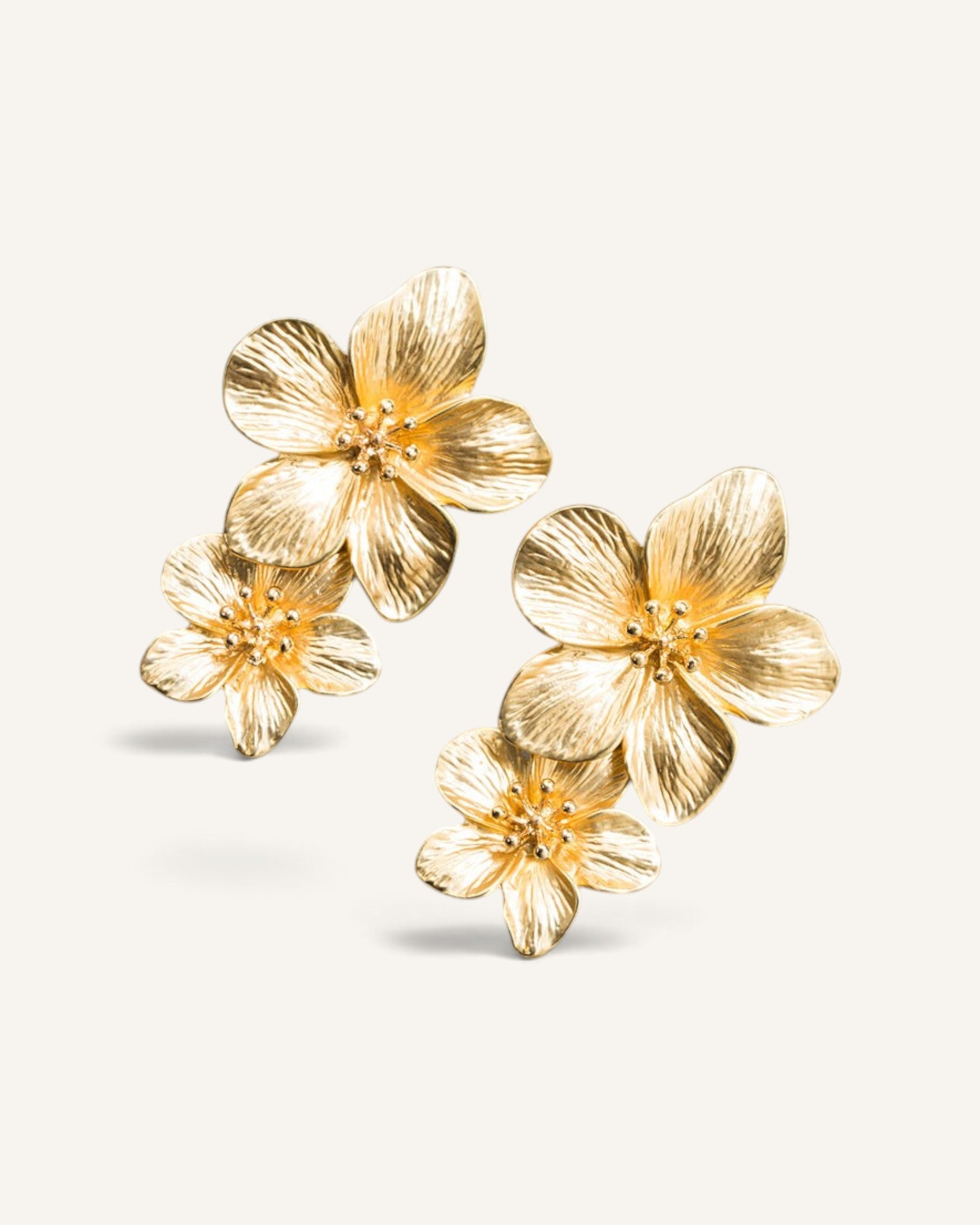 Lunéra de Paris gold statement earrings featuring a textured double floral design with layered botanical petals.