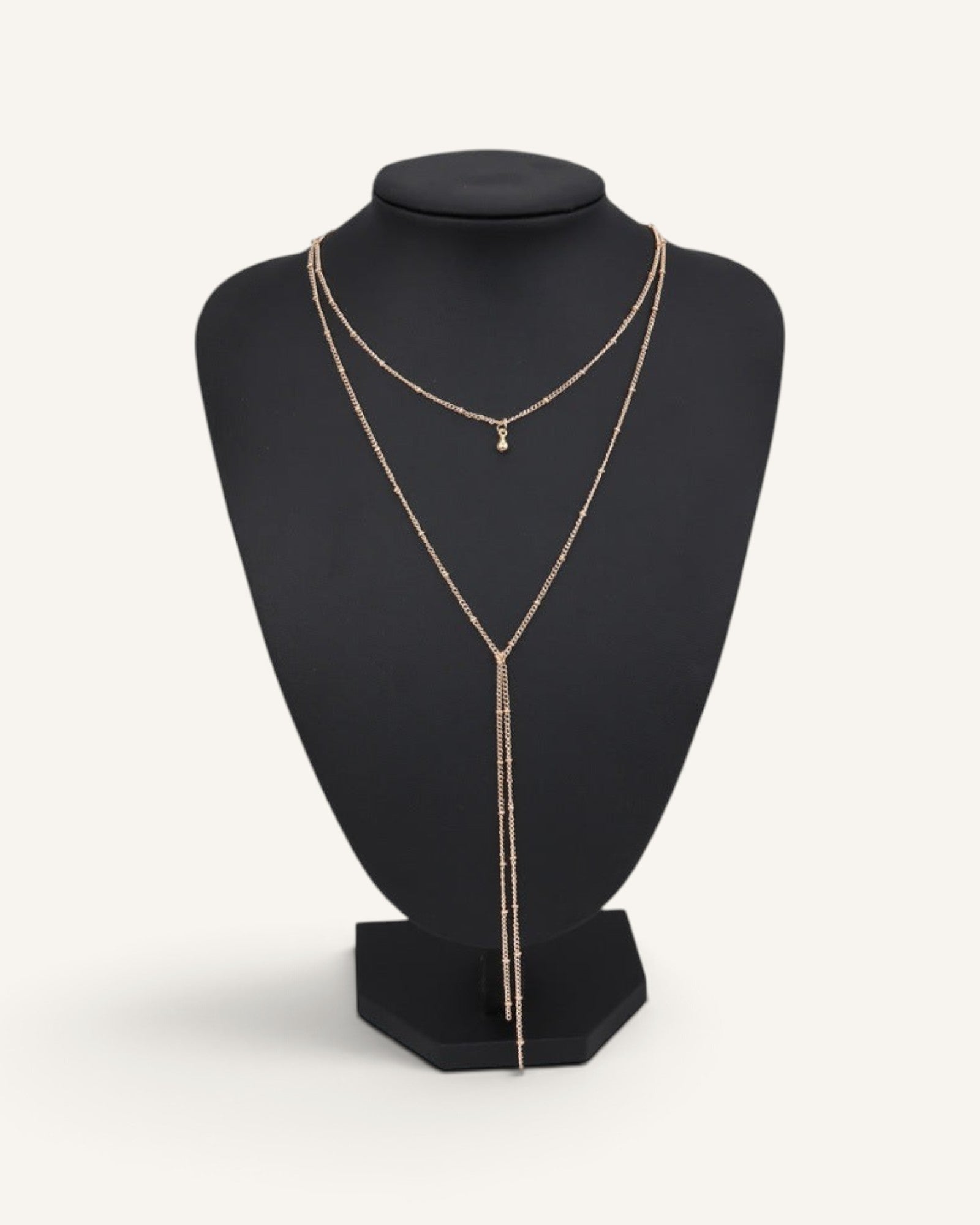 Lunéra de Paris double-layer gold lariat necklace with satellite chain and droplet pendant on a black display bust