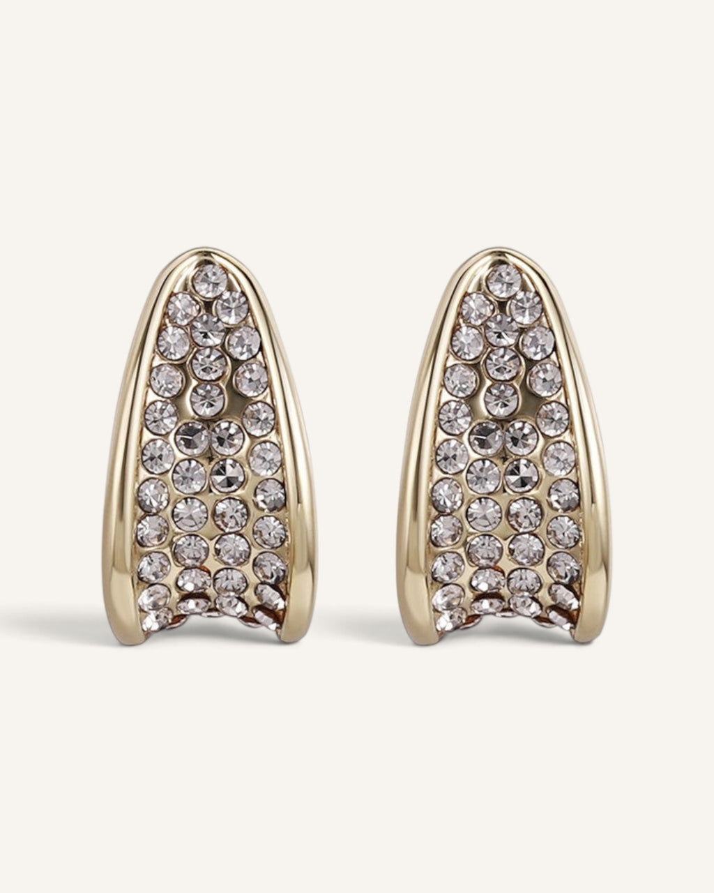 Lunéra de Paris gold-tone curved stud earrings featuring a sculptural tapered design with embedded clear crystals.
