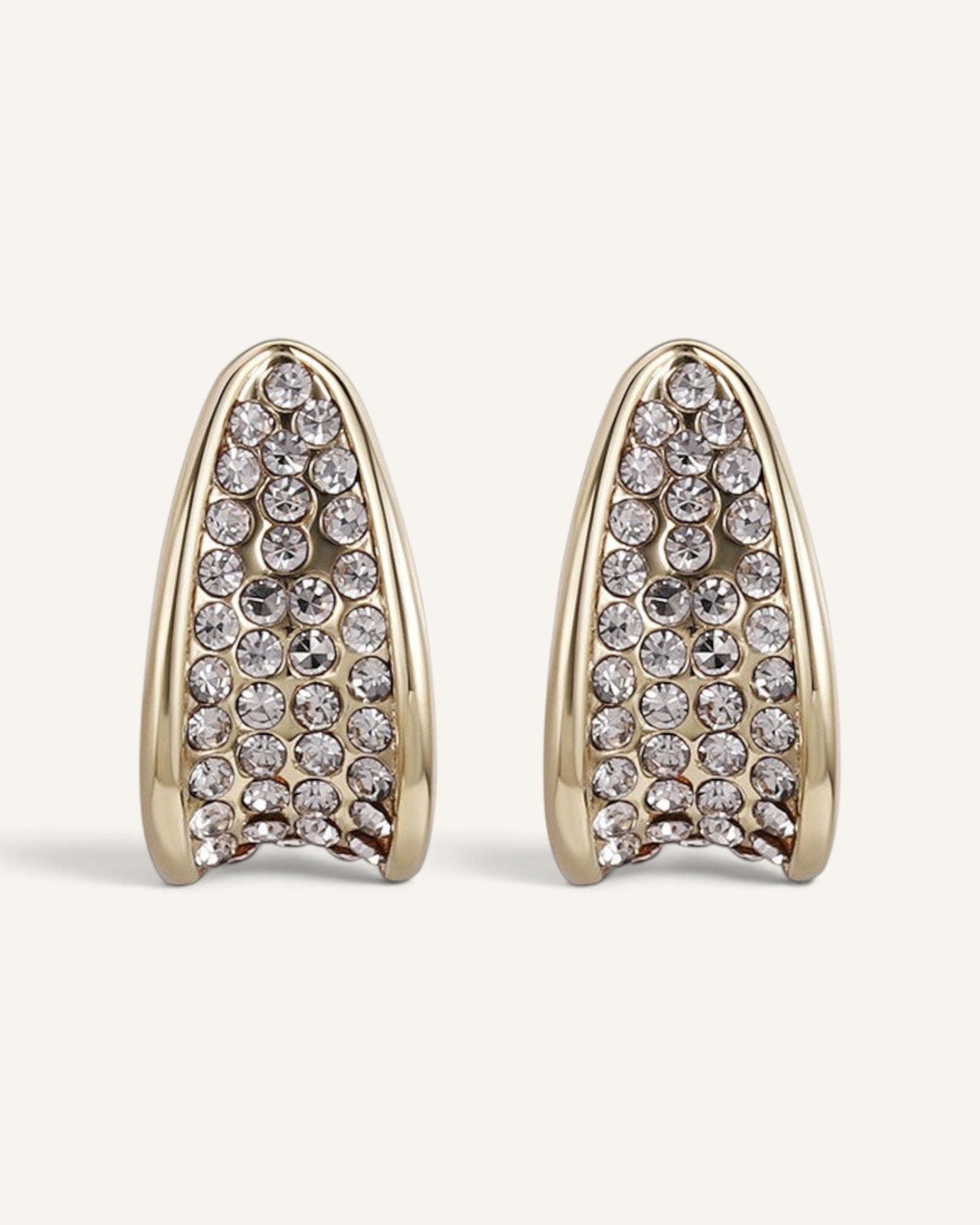 Lunéra de Paris gold-tone curved stud earrings featuring a sculptural tapered design with embedded clear crystals.