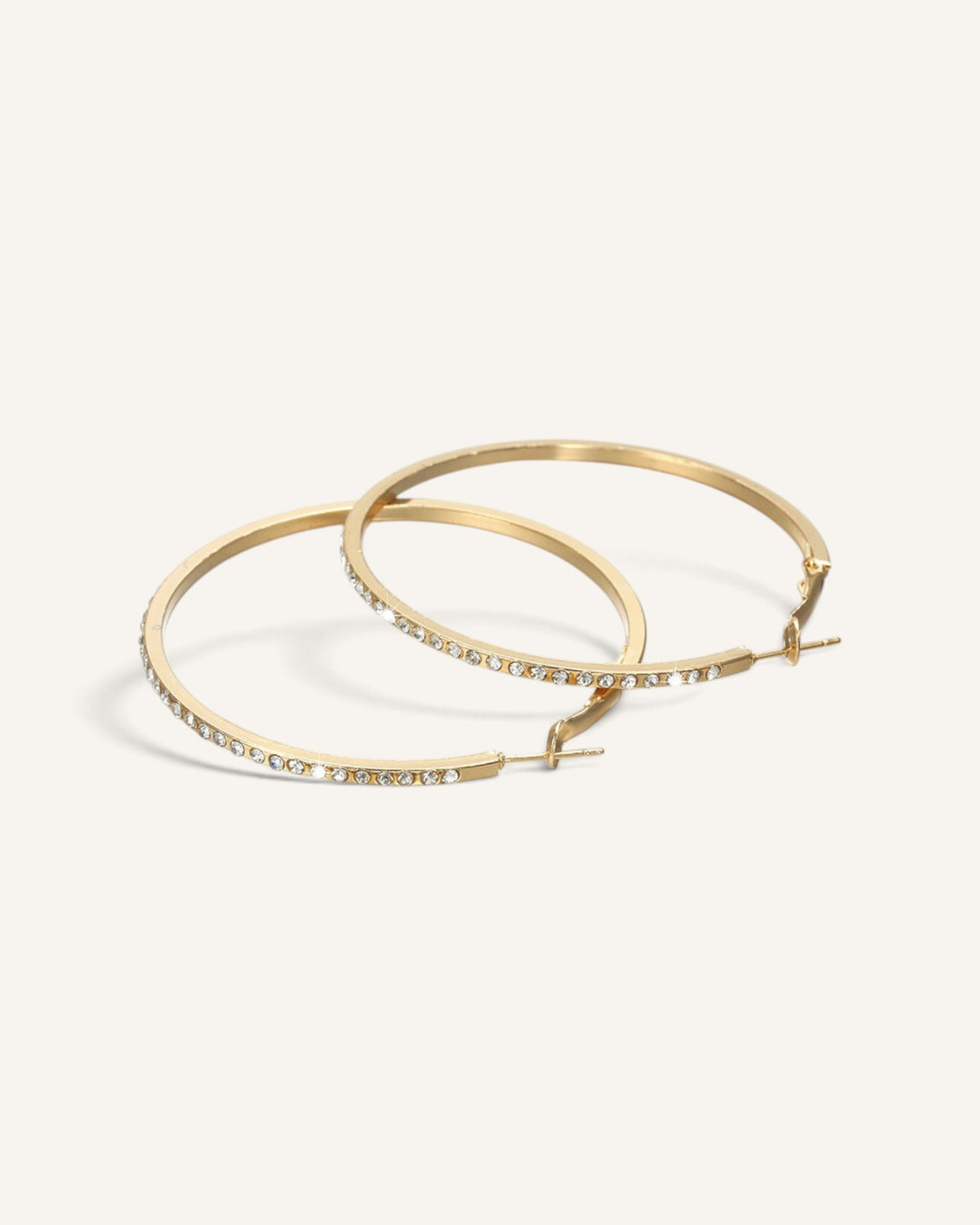 Lunéra de Paris gold hoop earrings with delicate pavé crystal accents and secure hinge closure on a neutral background
