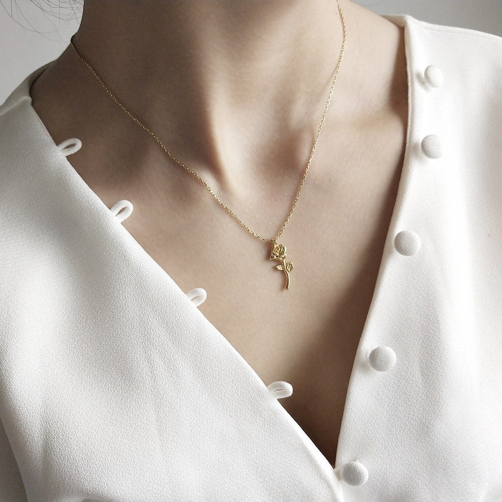 Lunéra de Paris gold-tone rose stem pendant necklace worn on a model in a white button-down top