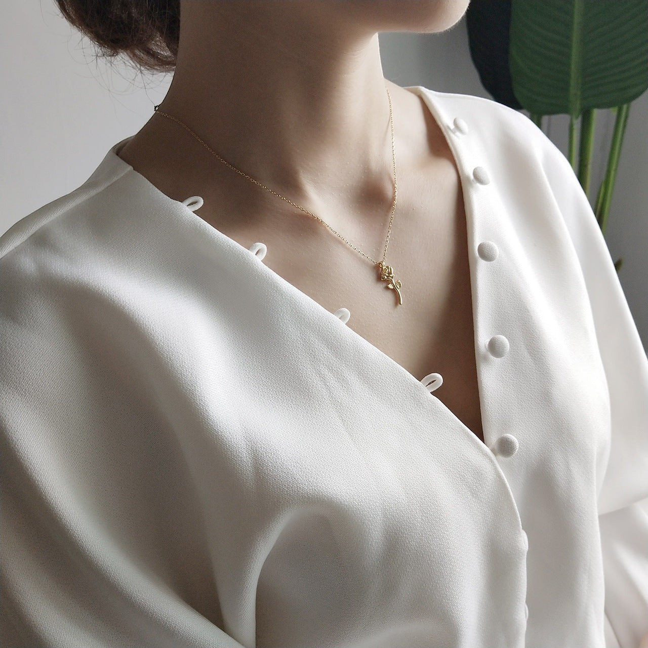 Lunéra de Paris gold-tone rose stem pendant necklace worn by a woman in a white button-down blouse