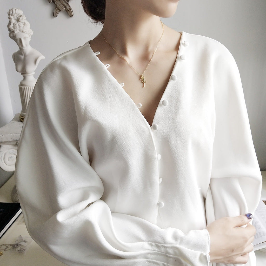 Lunéra de Paris gold-tone rose stem pendant necklace worn by a woman in a white button-down blouse