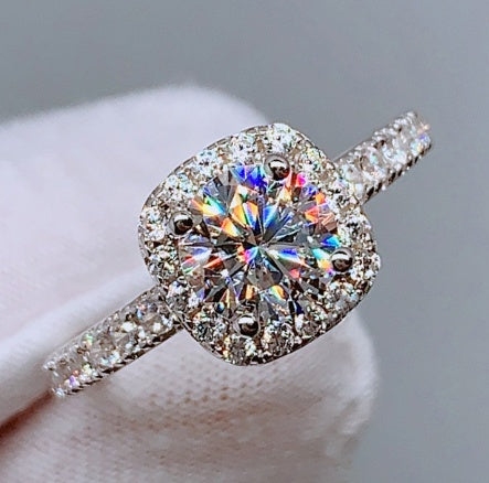 Lunéra de Paris round zircon halo solitaire ring with pavé accents on a silver band held by a gloved hand.