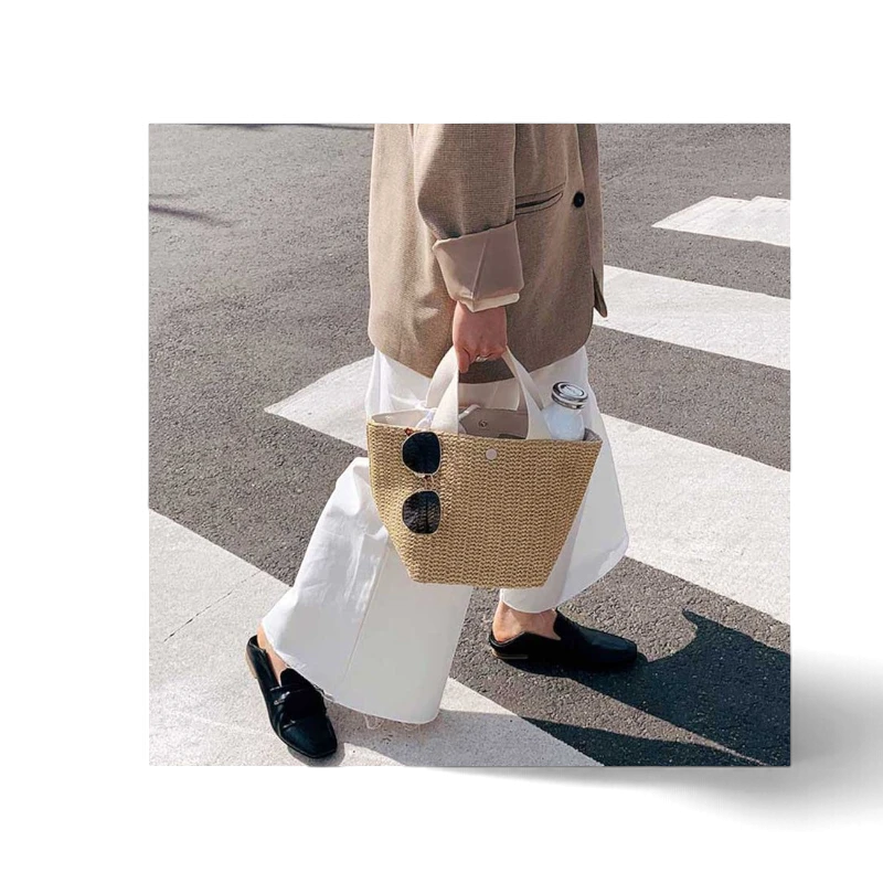 Lunéra de Paris Riviera woven beach bag with white top handles carried by a person in a blazer and white trousers