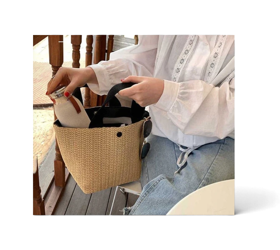 Lunéra de Paris Riviera woven beach bag with black top handles and a structured bucket silhouette held by a woman
