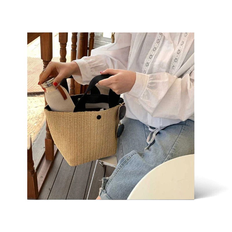 Lunéra de Paris Riviera woven beach bag with black top handles and a structured bucket silhouette held by a woman.