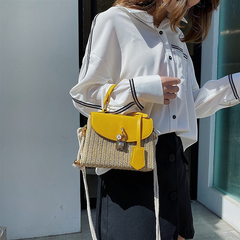Lunéra de Paris yellow and beige woven crossbody bag with a top handle, floral charm, and rope strap on a model.